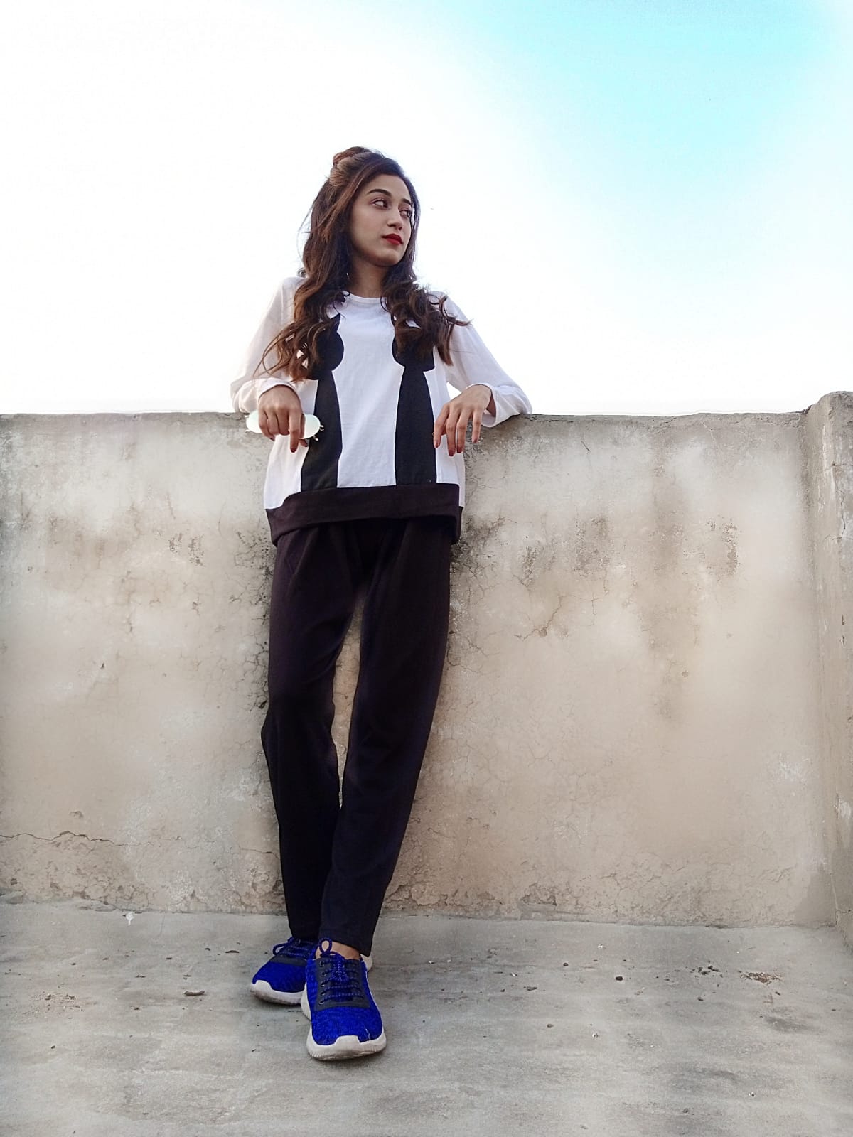 a woman standing on a sidewalk holding a skateboard 